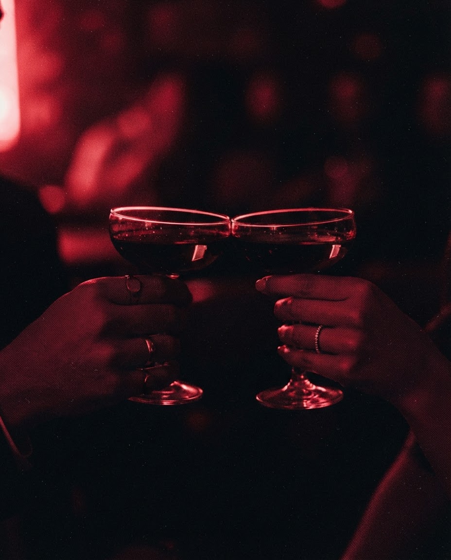 Two coupe glasses meeting in a toast under red light